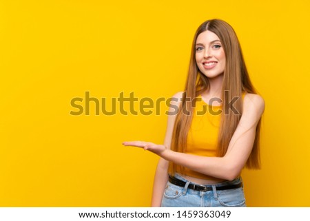 Young woman over isolated yellow background extending hands to the side for inviting to come