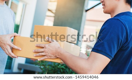 Asian Man hand accepting a delivery boxes from professional deliveryman at home Royalty-Free Stock Photo #1459414046