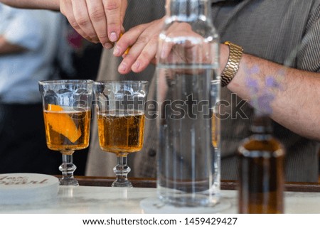 Bartender making fizzy orange drinks with orange peels at marble bar