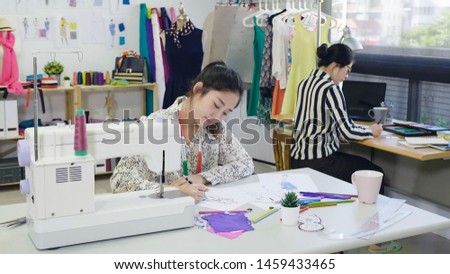 Two creative team fashion designers women drawing at sketches paper. skillful female dressmakers colleagues sitting at table brainstorming on new collection. ladies coworkers working in tailor shop.