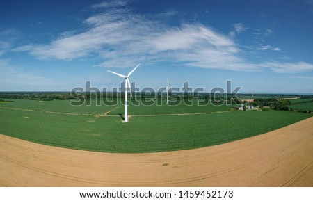 Aerial photo of onshore horizontal axis wind turbine (windmill) farm in green field with blue, sunny day. Ontario, Canada. Replenishable green renewable alternative energy and natural sources concept.