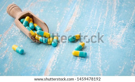 Vitamin and pharmaceutical medicine pills, tablets and capsules in wooden spoon on pastel blue background. Dietary supplement healthcare product. Concept of health