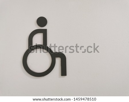 Disable person sign for restroom on wall. Handicapped accessible restroom.