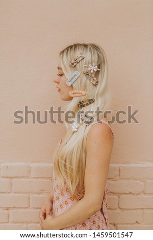 Blonde Woman with Acrylic and Pearl Clips in her hair, model wearing resin hair barrettes, modern hair pins on girl, pink brick wall background