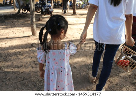 Mom is holding a small daughter's hand with love, taking blurred pictures