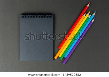 black notebook and lgbt colored pencils on black background. Mock Up Notebook of black paper and lgbt colored pencils are lying on paper background. Copy space.
