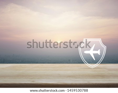 Airplane with shield flat icon on wooden table over aerial view of cityscape at sunset, vintage style, Business travel insurance and safety concept