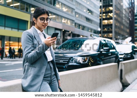 Hispanic woman professional regional manager reading sms in group office chat while standing at urban setting with smartphone for communication, successful female proud ceo chatting via app