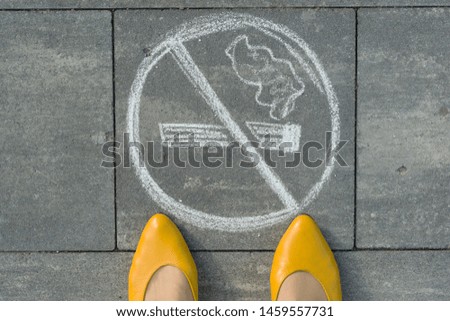 Female feet with picture no smoking painted on the grey sidewalk.