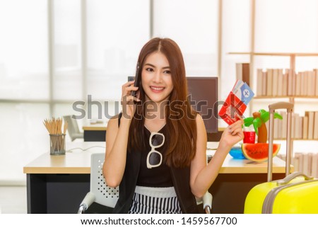 Beautiful Asian business woman smiling holding passport and talking mobile phone with yellow suitcase to prepare traveling for travel tourist on holiday weekend. Business and travel concept.