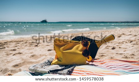 Towel, beach tennis racquet and sunglasses in the beach. Accessories for the beach and summer.