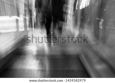 Artistic black and white image of person on the way to work in the city. People rushing to work - blurred figures coming out of the subway. Pepople in the hurry.