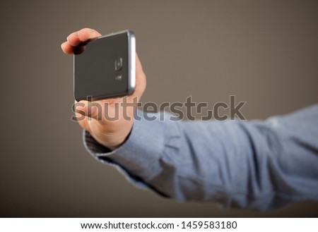 Unrecognizable man's hand taking photo with a smartphone, dark grey background