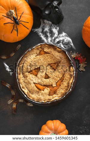 Halloween Pumpkin Pie, Pumpkins and Halloween Decor on dark background, top view. Homemade dessert idea for Halloween.
