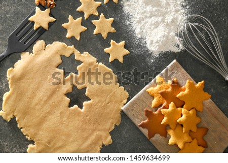 Raw and baked Christmas cookies on dark background