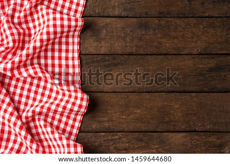 Red checkered tablecloth on wooden background 