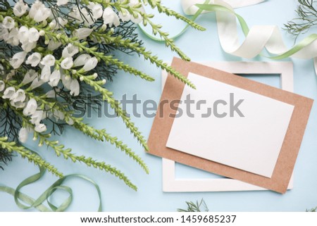 Postcard mockup with white flowers on a blue background and envelope