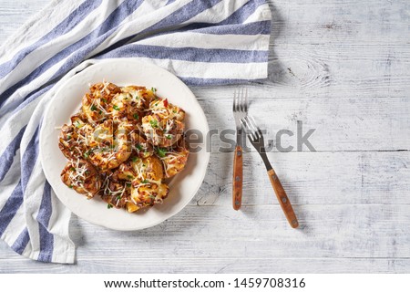 Savory smashed potatoes with parmesan cheese and parsley on top, served with forks on a white plate on a white wooden table, top view, horizontal, copy space Royalty-Free Stock Photo #1459708316