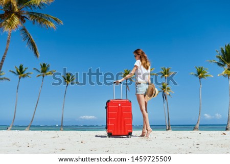 Traveler with a red suitcase in shorts and a tank top walks on the island bottom view                         