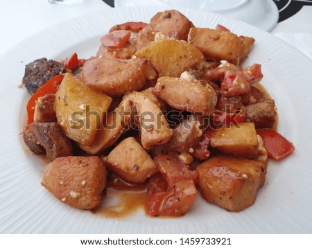 Greek Village Style Dish on a White Plate, Pork, Chicken, Sausage, Potatoes, Peppers and Feta Cheese, Delicious Restaurant Tasty Dish with Tomato Sauce, Traditional Greek Food