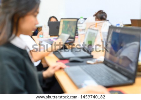 Blurred images of young business people are using computer notebooks.