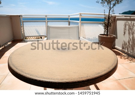 Table background on a beautiful blue sky and ocean view. Empty space on a round wooden table top for an advertising product.