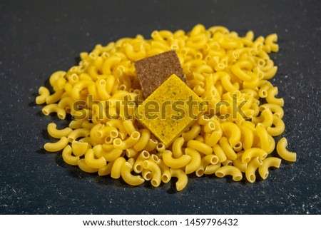 Pasta horns and bouillon cube on a black background, delicious food