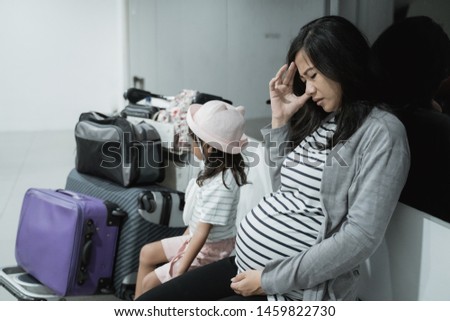 pregnant women with headaches and his daughter when sitting together in the waiting room airport