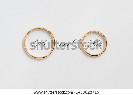 Golden wedding rings on white paper.
