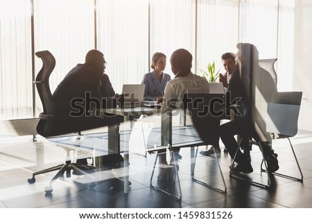 Silhouettes of people sitting at the table. A team of young businessmen working and communicating together in an office. Corporate businessteam and manager in a meeting Royalty-Free Stock Photo #1459831526