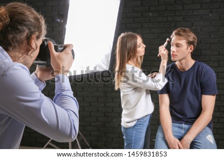 Photographer, makeup artist and model in modern studio