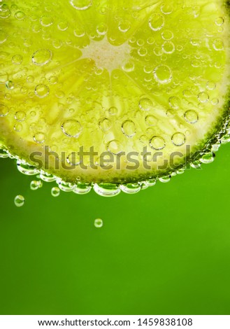 Close up of water with lime slice and bubbles. Macro shot