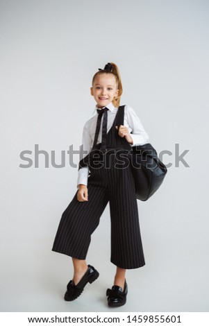 Girl preparing for school after a long summer break. Back to school. Little female caucasian model posing in school's uniform with backpack on white background. Childhood, education, holidays concept.