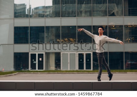 Young male ballet dancer on a building background. Outdoor dance.