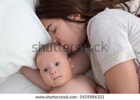 A brunette woman kisses a baby. Mom with baby closeup