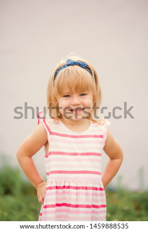 Pretty little girl standing on pink background and holding ponytails on her head.