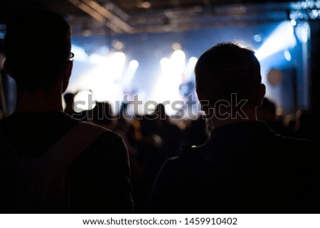 Cheering people crowd in concert show having fun and applause in front of stage lights