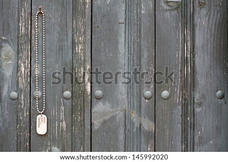 Dog tag hanging on old black wood wall background