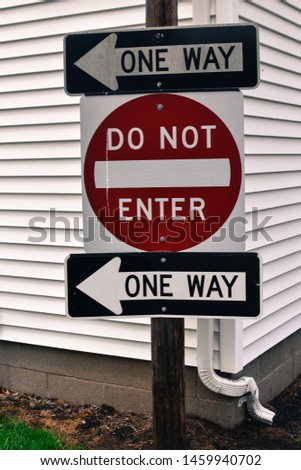 street signs reading one one and do not enter stacked on top of each other white shingles exterior background