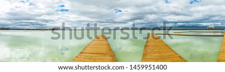 Over the vast salt lake, there are long wooden sidewalks. The beautiful scenery of Chaka Salt Lake is in the summer in Qinghai Province, China.