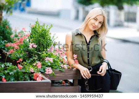 Young beautiful blonde girl standing in the middle of town in glasses. The girl is well dressed. The girl is ready for a business meeting