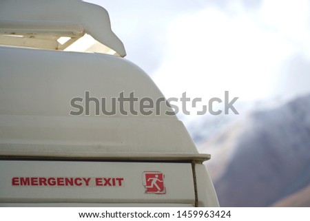 "Emergency Exit" sign on a white van with blurred himalayas mountain background, Leh Ladakh, Jammu and Kashmir, North India. For safety transportation.