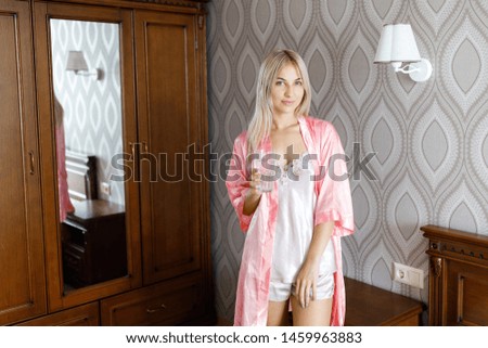 A young beautiful blonde girl wakes up in the morning and drinks water.