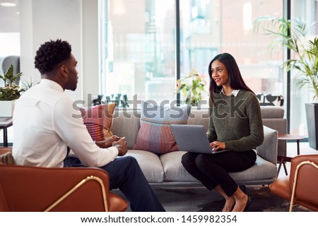 Businesswoman Interviewing Male Job Candidate In Seating Area Of Modern Office Royalty-Free Stock Photo #1459982354