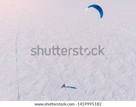 Male athlete on mountain skiing with dreams kite free ride on frozen lake. Aerial view. Snowkiting. Royalty-Free Stock Photo #1459995182