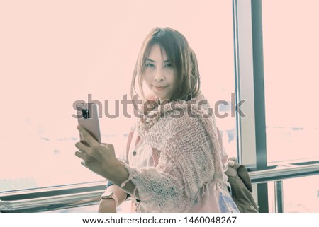 Beautiful young Travelling Asian Woman with Clean, Fresh, Glow, and pefect Skin selfie with mobile phone at international airport.