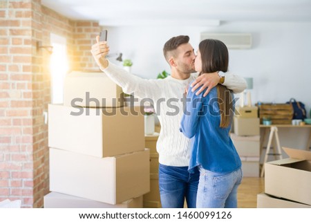 Beautiful couple taking a selfie photo using smartphone at new apartment, smiling happy for new house
