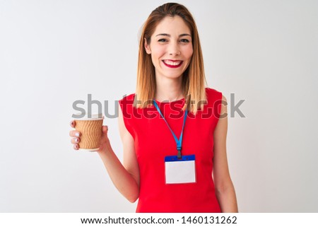 Redhead businesswoman wearing id card drinking cup of coffee over isolated white background with a happy face standing and smiling with a confident smile showing teeth