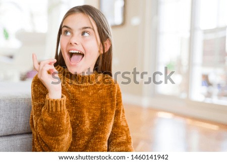 Beautiful young girl kid wearing casual sweater cheerful with a smile of face pointing with hand and finger up to the side with happy and natural expression on face