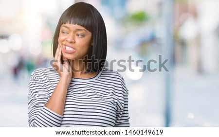 Beautiful young african american woman wearing stripes sweater over isolated background touching mouth with hand with painful expression because of toothache or dental illness on teeth. 